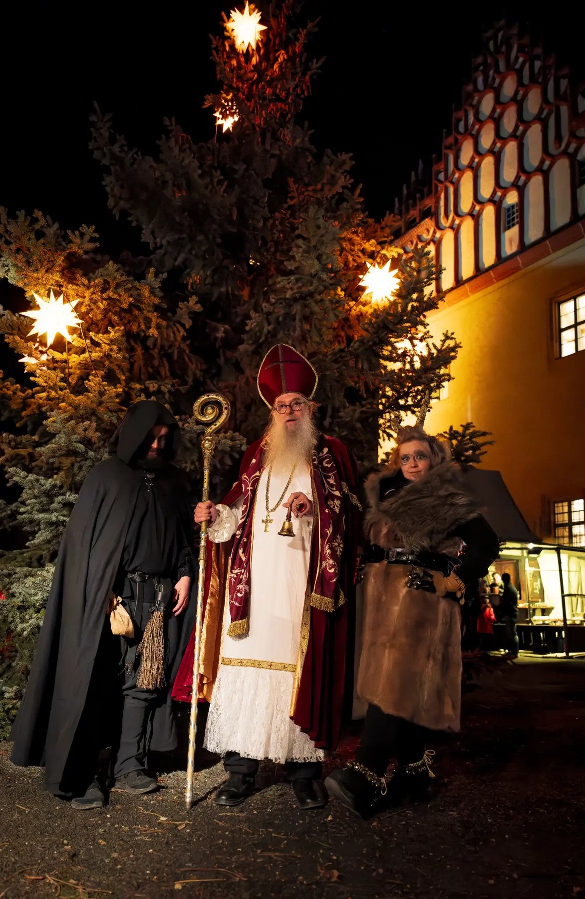 Der Nikolaus mit Krampus und Knecht Ruprecht im weihnachtlich beleuchteten Schlosshof