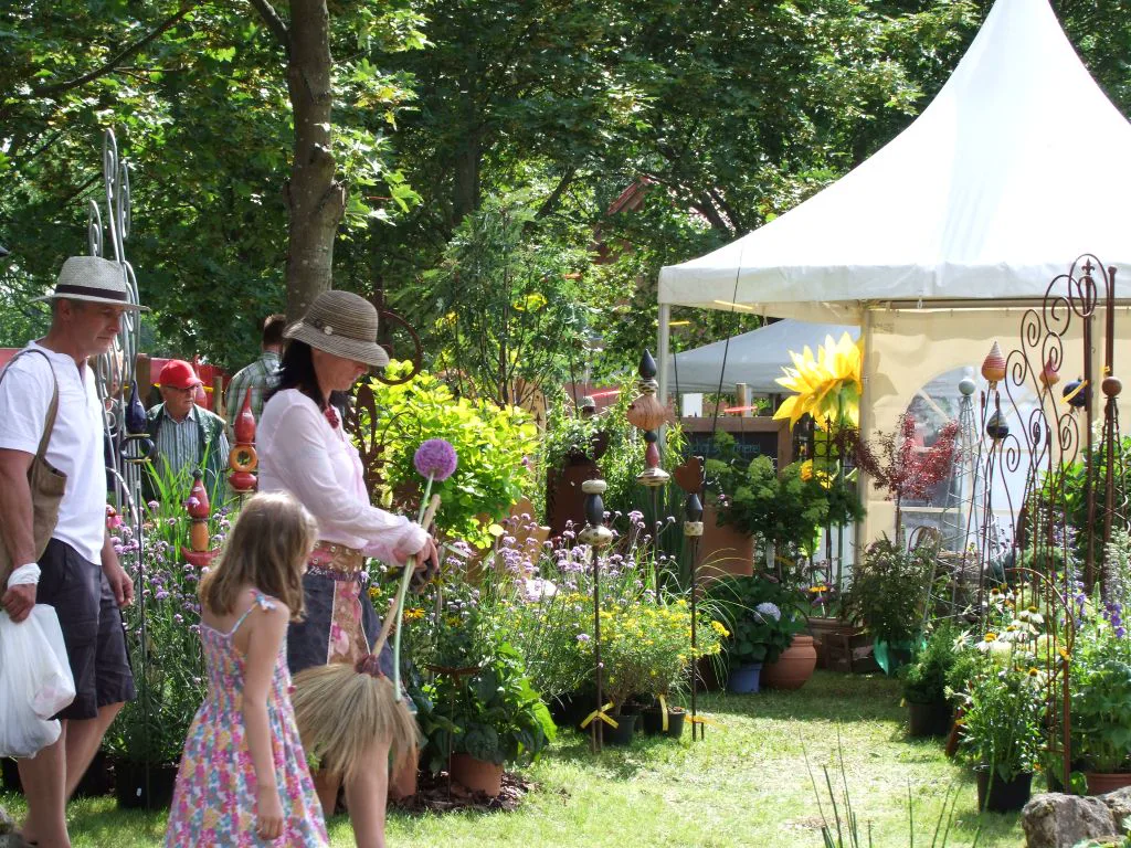 Besucher zwischen Pflanzen und Gartenständen im Schlosspark